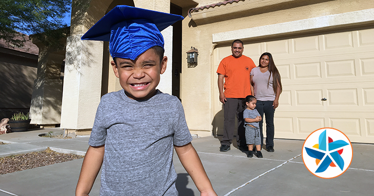 Little boy in graduation cap with family behind him