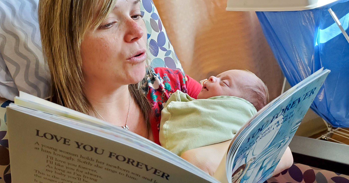 NICU nurse reading book to newborn