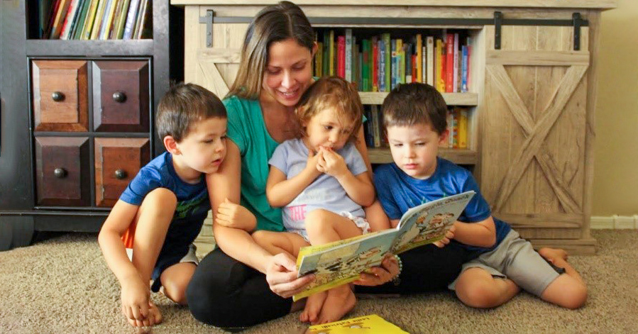 Mother reading to her children that are sitting next to her on the floor